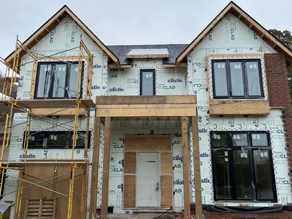 Front elevation of a two storey custom residential build under construction in Toronto showing a newly framed wood front porch and concrete steps.